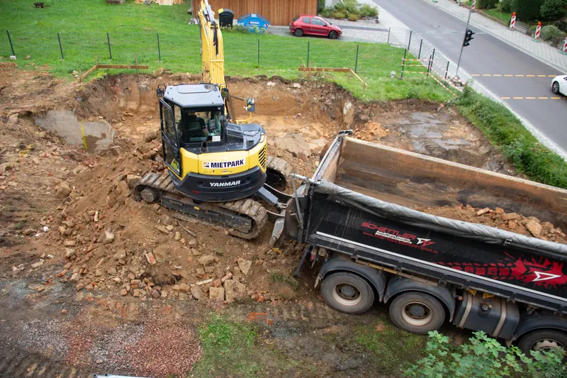 Bagger lädt den Erdaushub der Baugrube auf einen Lkw