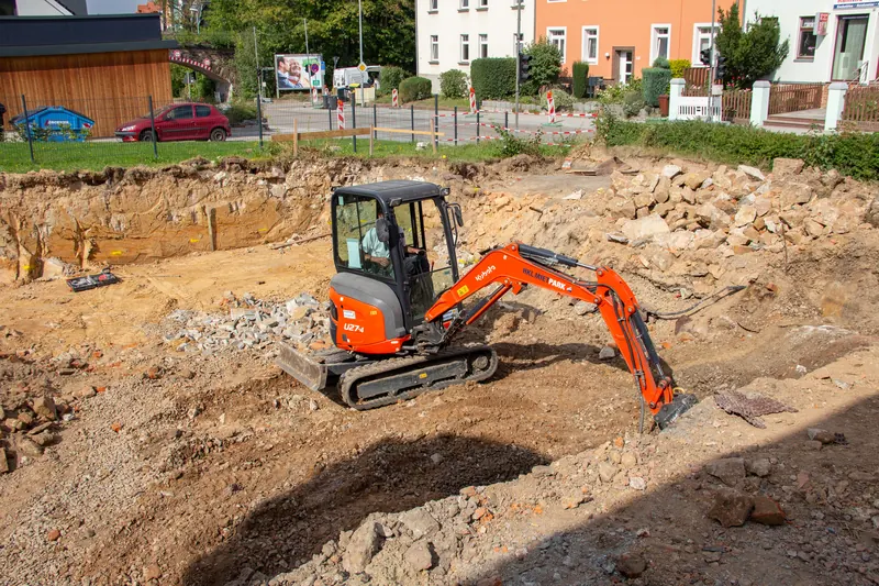 Minibagger arbeitet in der ausgehobenen Baugrube