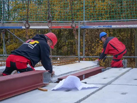 Zwei Monteure richten die Deckenelemente auf den Wänden aus