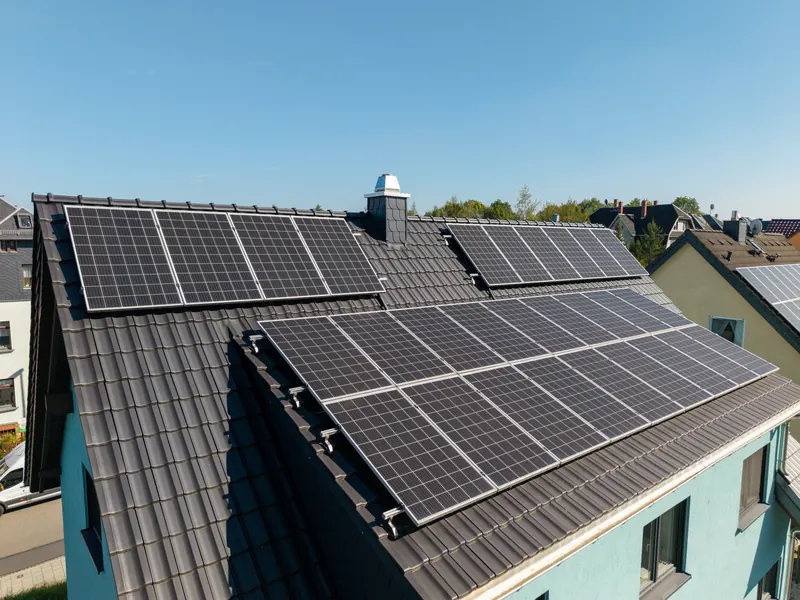 Photovoltaikanlage auf dem dunklen Satteldach des fertigen Hauses