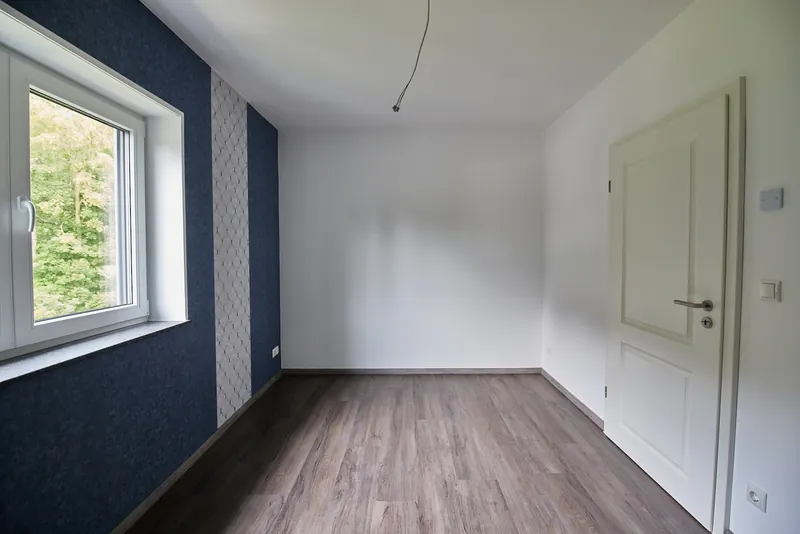 Fertiges Zimmer mit dunkler Akzentwand und großem Fenster