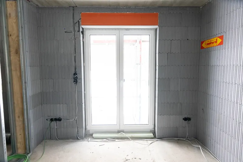 Raum im Innenausbau mit eingebauter Fenstertür und vorbereiteter Elektroinstallation