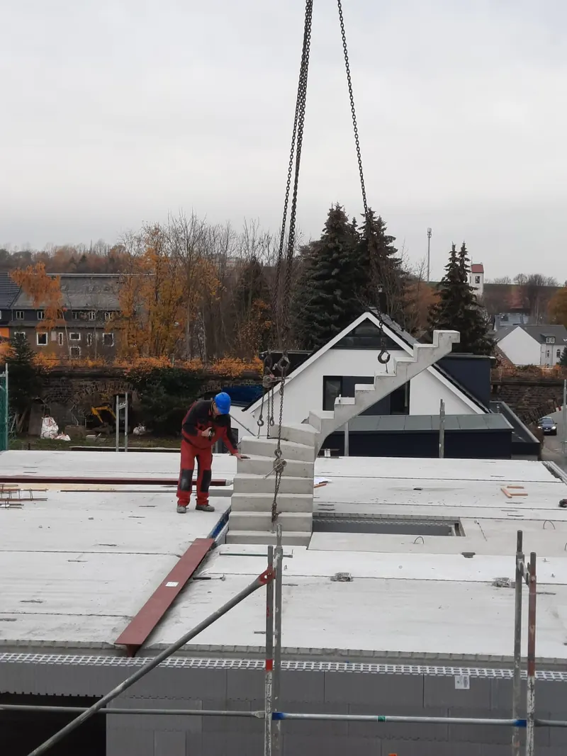 Eine fertige Treppe wird mit dem Kran auf die Decke gehoben