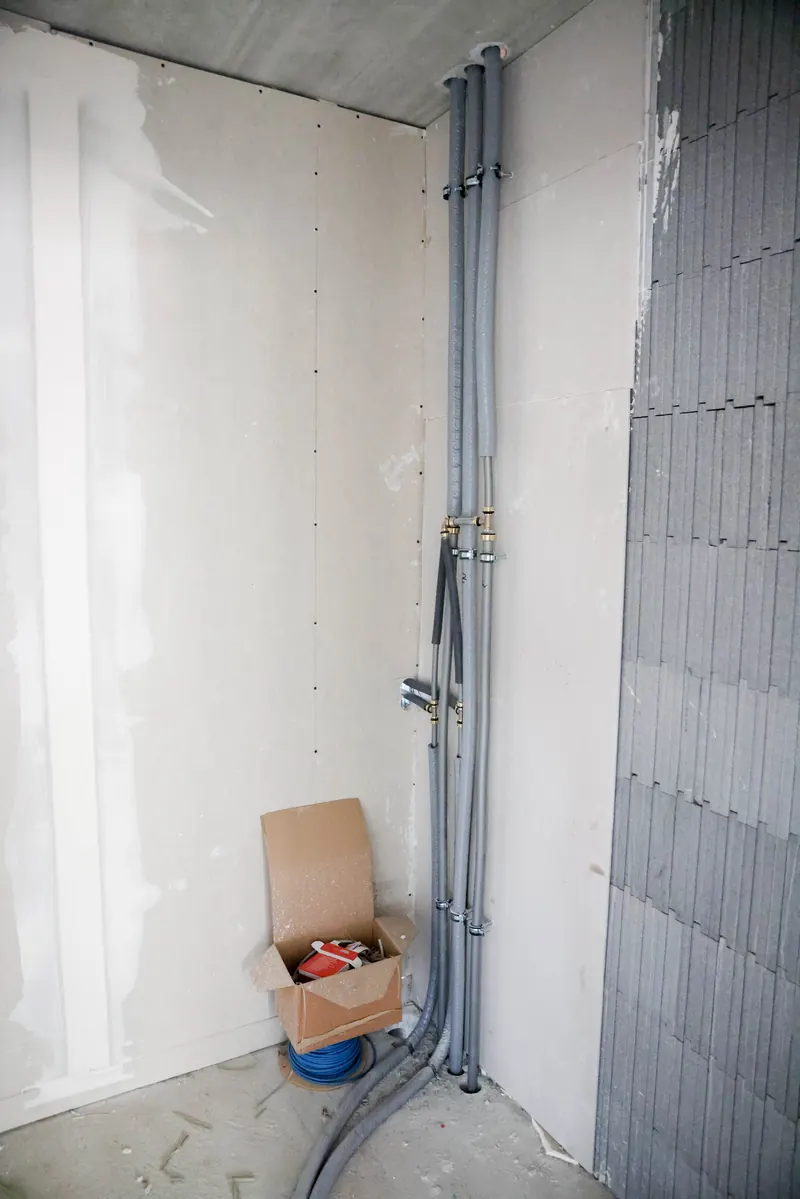 Mit Gipskarton verkleidete Wand neben noch offener isorast-Wand und Installationsleitungen