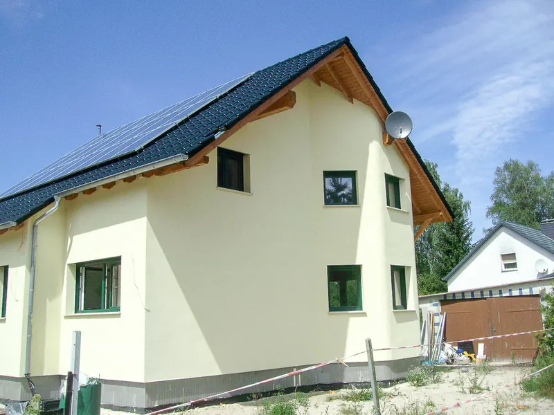 Hellgrünes Einfamilienhaus mit Photovoltaikanlage auf dem Satteldach