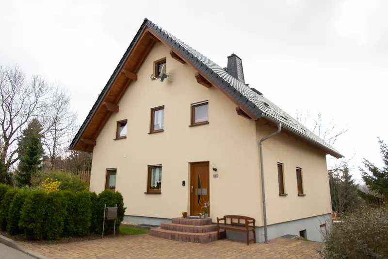 Beiges Einfamilienhaus mit Satteldach und Holzhaustür