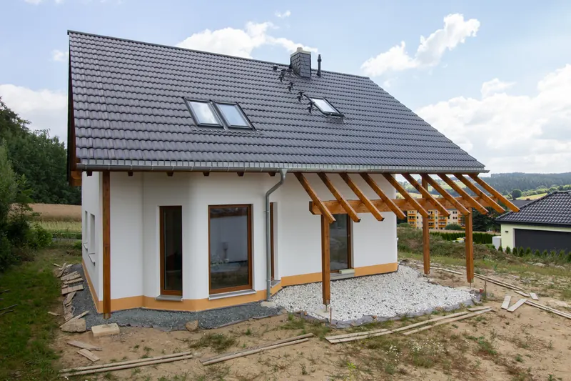 Weißes Einfamilienhaus mit Holzpergola und großen Fensterflächen