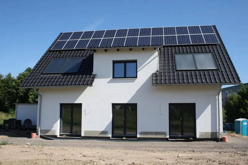 Weißes Einfamilienhaus mit Satteldach und Photovoltaikanlage