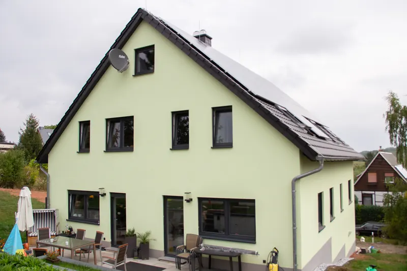 Hellgrünes Einfamilienhaus mit Terrasse und Garten