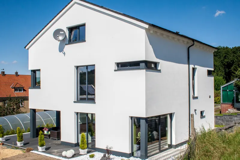 Weißes, modernes Einfamilienhaus mit großen Fenstern