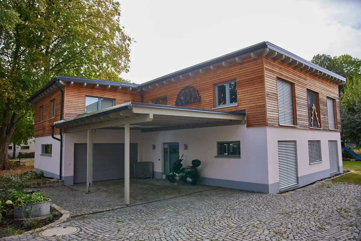 Modernes Einfamilienhaus mit Holzfassade, Flachdach und Carport