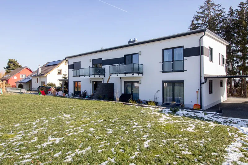 Gartenseite des weißen Mehrfamilienhauses mit Balkonen im Winter