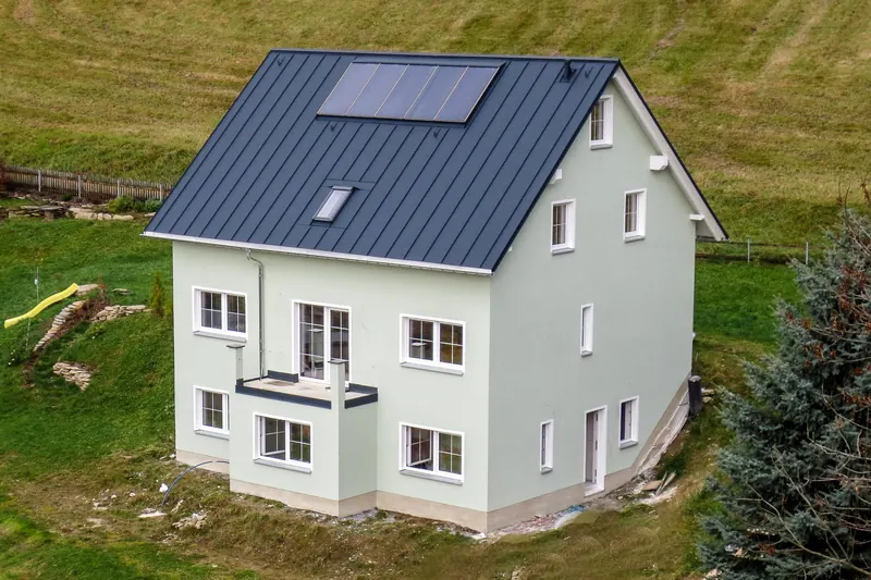 Luftbild: Passivhaus mit dunklem Metalldach in Hanglage